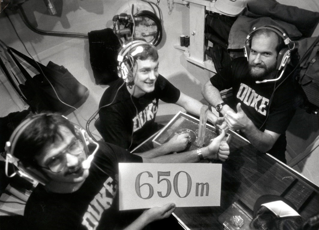 Divers hold up a sign to indicate they are not at a simulated 650 meter (2,132 feet) dive during one of the Atlantis dives. 